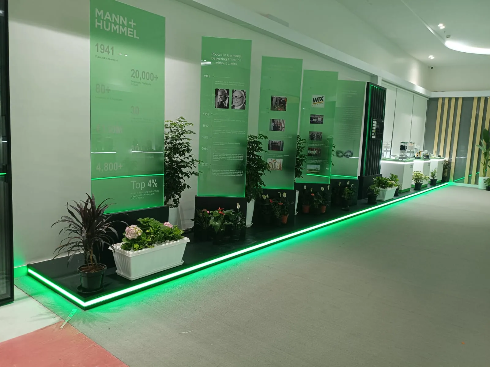 Freestanding green graphic pylons and planters on a raised plinth edged with a continuous green LED line
