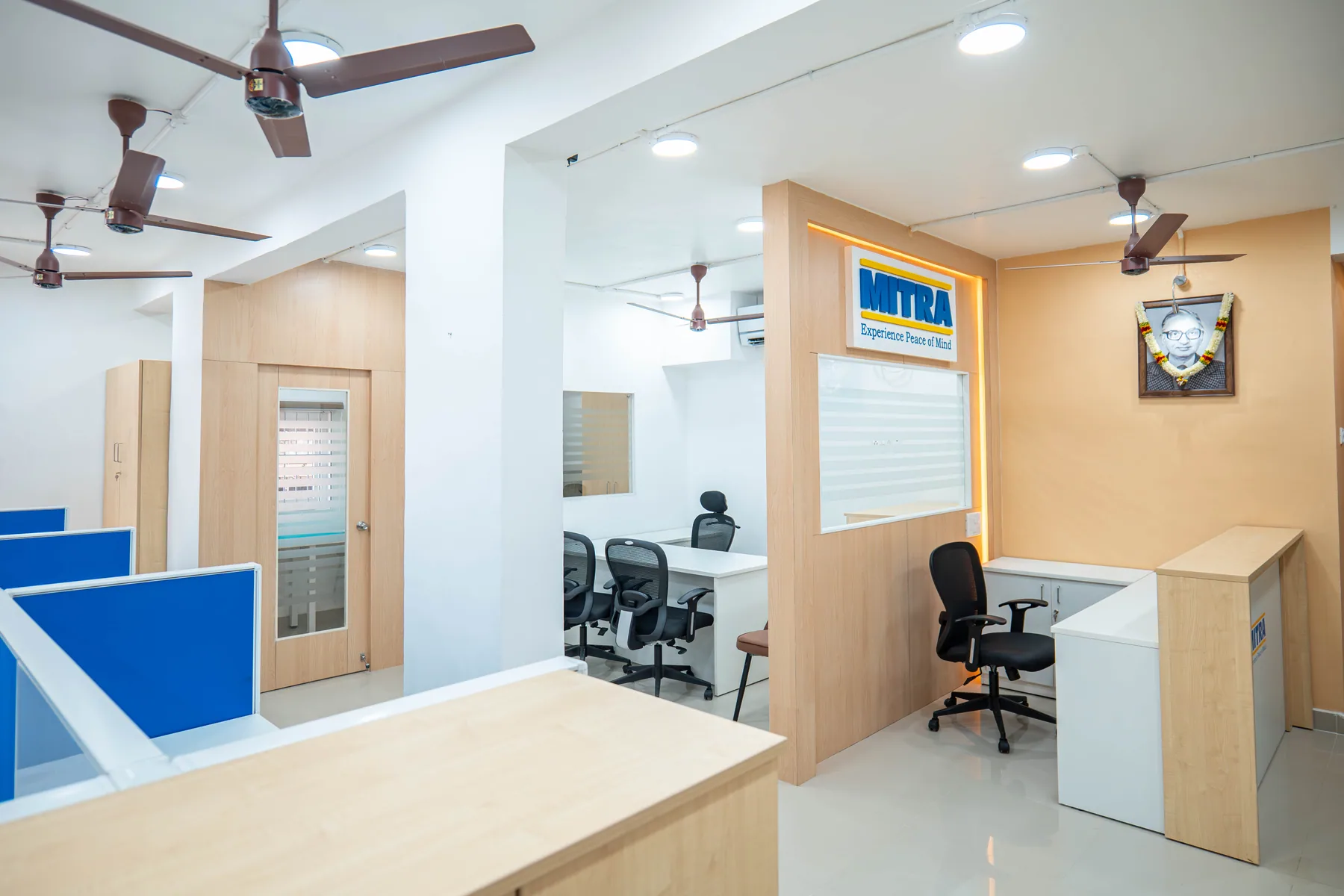 A completed office fit-out with a cove-lit timber reception volume, white partitions and a polished floor running back through two further rooms